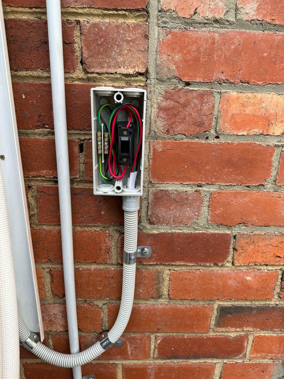 Weatherproof isolator and neat conduit run for a split system's dedicated circuit on a brick wall