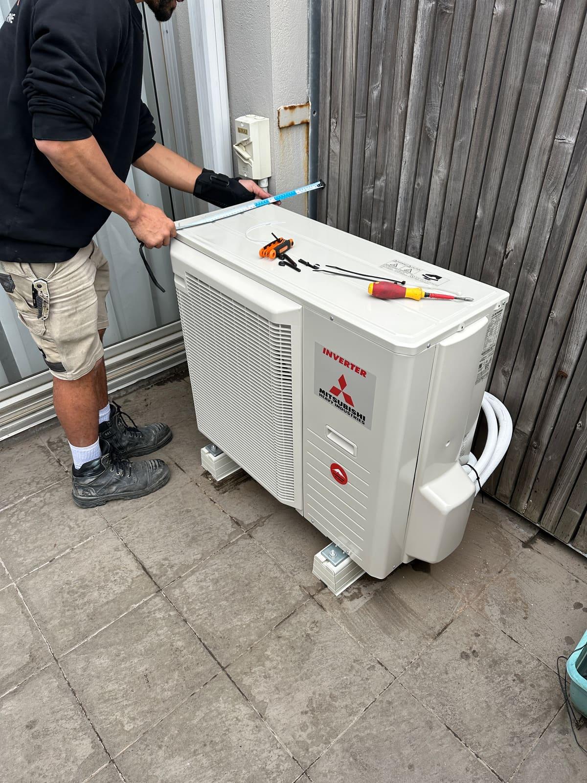 True Line technician measuring up a Mitsubishi Heavy Industries outdoor unit during final fit-off at a southeast Melbourne home